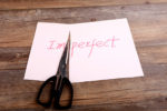 49789881 - a scissor cuts perfect from imperfect on the desk.